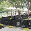 Black decorative lattice resin patio fencing creating sidewalk café dining enclosure with umbrellas and outdoor tables