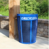Blue 48 gallon expanded metal recycling receptacle installed outdoors along a concrete walkway near a stone wall