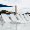Multiple white Forma luxury in-pool chaise lounges arranged on a commercial pool tanning ledge