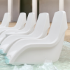 White Forma commercial in-pool lounge chairs arranged on a shallow pool tanning ledge