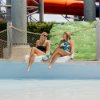 Guests relaxing on white Forma commercial pool edge chairs beside a swimming pool