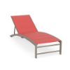 Three-quarter front view of a commercial pool deck chaise lounge featuring a padded sling design, beige Satin Amber arched frame, and bright coral pink Straw Mat textured cushioned fabric.