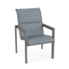 Front three-quarter perspective view of a commercial outdoor padded dining chair with a metallic Titanium Gray aluminum frame, angular armrests, and a slate blue Kozo Jewel textured padded sling.