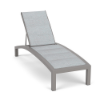 A front three-quarter view of a commercial patio chaise lounge featuring a neutral Calypso powder-coated frame with a light grey patterned Interlock padded sling surface.