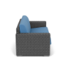Side profile view of a dark gray woven resin wicker commercial outdoor loveseat fitted with vibrant sky blue seat and back cushions.