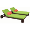 A double-wide commercial outdoor chaise lounge featuring a Java chocolate brown woven wicker frame, bright lime green cushions, and two small coral red headrest pillows on an isolated white background.
