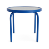 Front perspective view of a 20-inch round Sundance commercial outdoor side table featuring a vibrant Marina blue powder-coated aluminum frame, four curved tubular legs, and a textured acrylic tabletop surface, isolated on a white background.