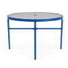 A 42-inch round commercial outdoor dining table with a textured clear acrylic top featuring a center umbrella hole, supported by a vivid Marina blue powder-coated aluminum frame with tubular straight legs, cross-bracing, and black foot glides.