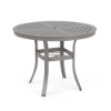A 36-inch round aluminum commercial patio dining table in a Platinum powder-coated finish, built with curved legs, a lower umbrella support ring, and a slated tabletop pattern with an umbrella opening.