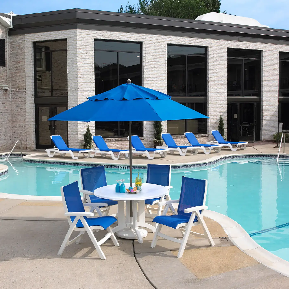 Modern commercial pool deck with Royal Blue Jamaica Beach dining chairs and matching Marina chaise lounges surrounding the swimming pool.